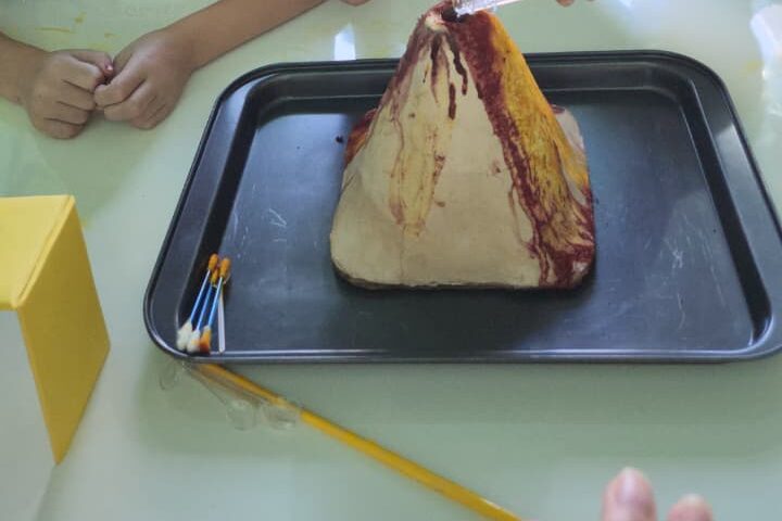 Experiência do vulcão montada em bandeja, com pincéis ao lado
