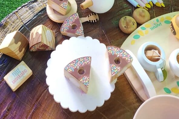 Mesa de faz de conta com bolinhos e xícaras de madeira