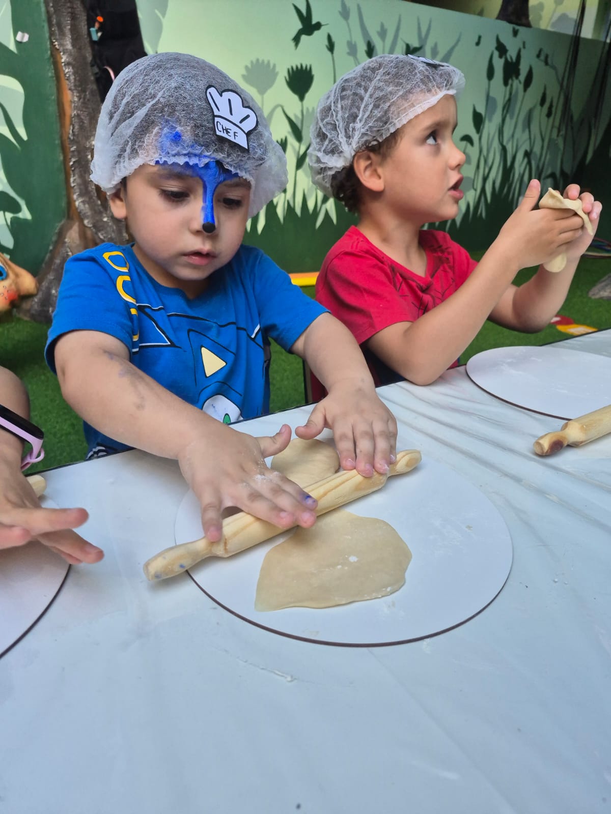 Criança de avental na Oficina de Pizzaiolo Mirim da Galeria Materna.